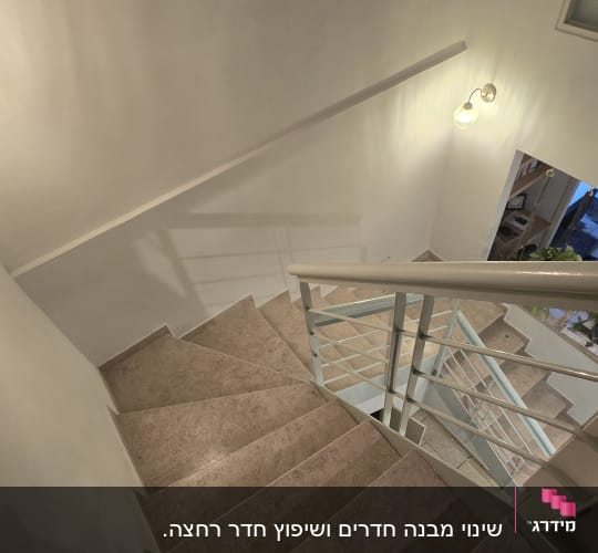 מדרגות משופצות עם מעקה מתכת ותאורה על הקיר